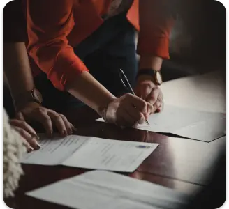 Imagem de pessoas assinando um contrato sobre a mesa